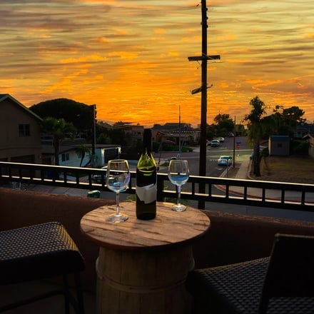 Rooftop deck with wine glasses and blazing orange sunset