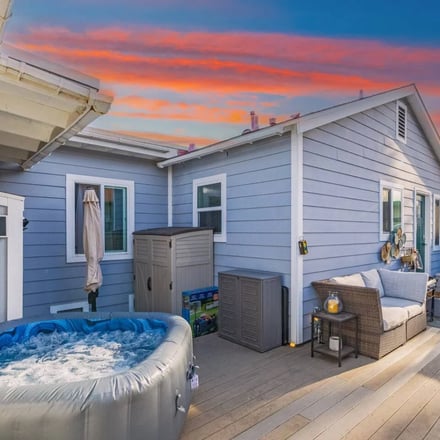 Back deck with hot tub and coastal home exterior at sunset