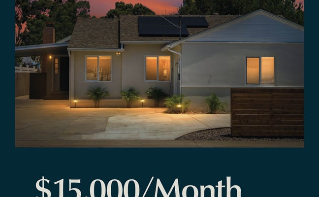 Modern single-story home with illuminated windows and solar panels at dusk, dramatic sunset sky behind